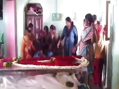 Relatives Laughing and Dancing in Front of Dead Man in Coffin 
